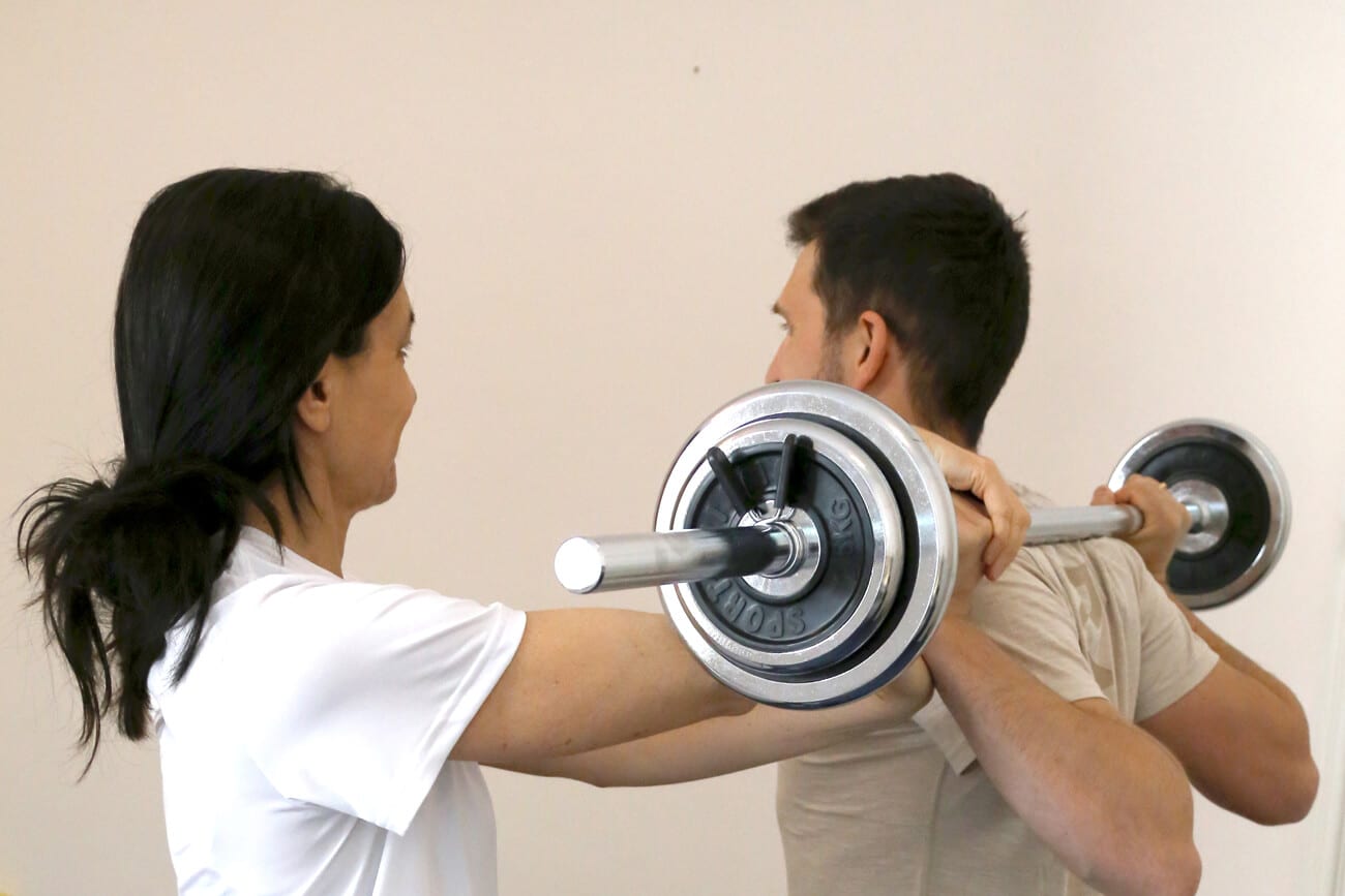 Physiotherapie Hilfe beim Training mit Langhantel